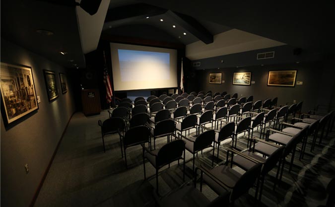 Interior of Munger Theater with chairs set out and screen in background.