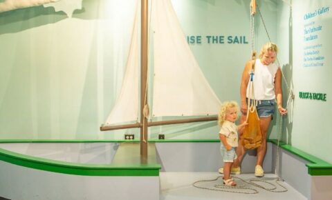 Two SBMM visitors raise the sail on the sailboat in the Children's Gallery.