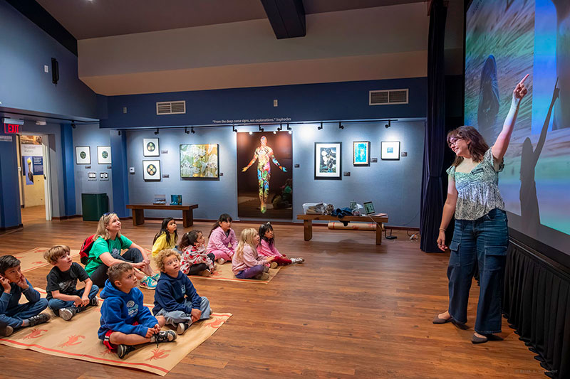 Museum volunteer telling stories to a group of kids on a field trip